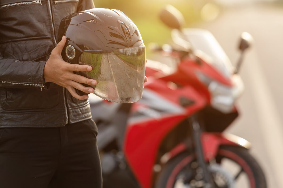 ヘルメットを持つライダーと赤いバイク